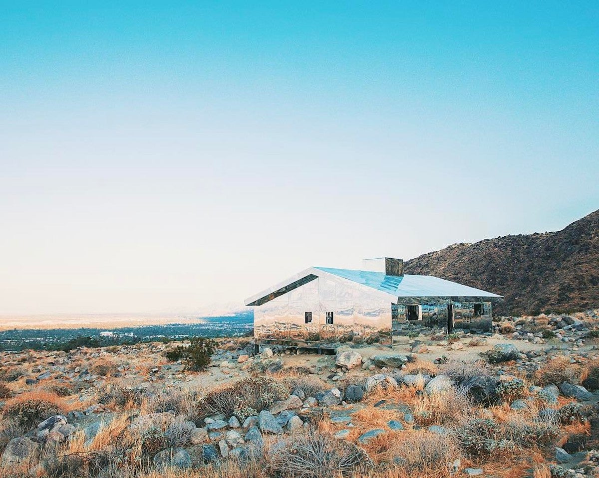 Mirrored house reflecting the views of a desert prairie with mountains in the background