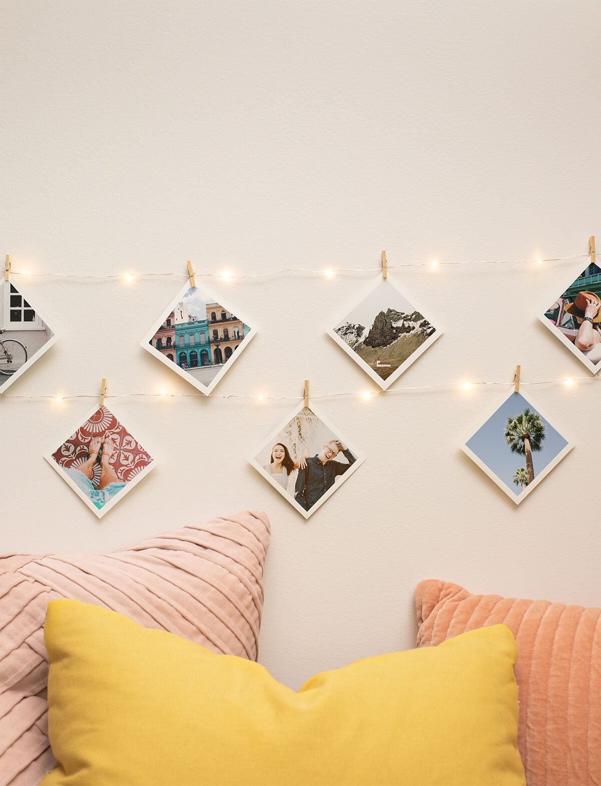 Diagonally rotated square prints hanging from lit up string lights