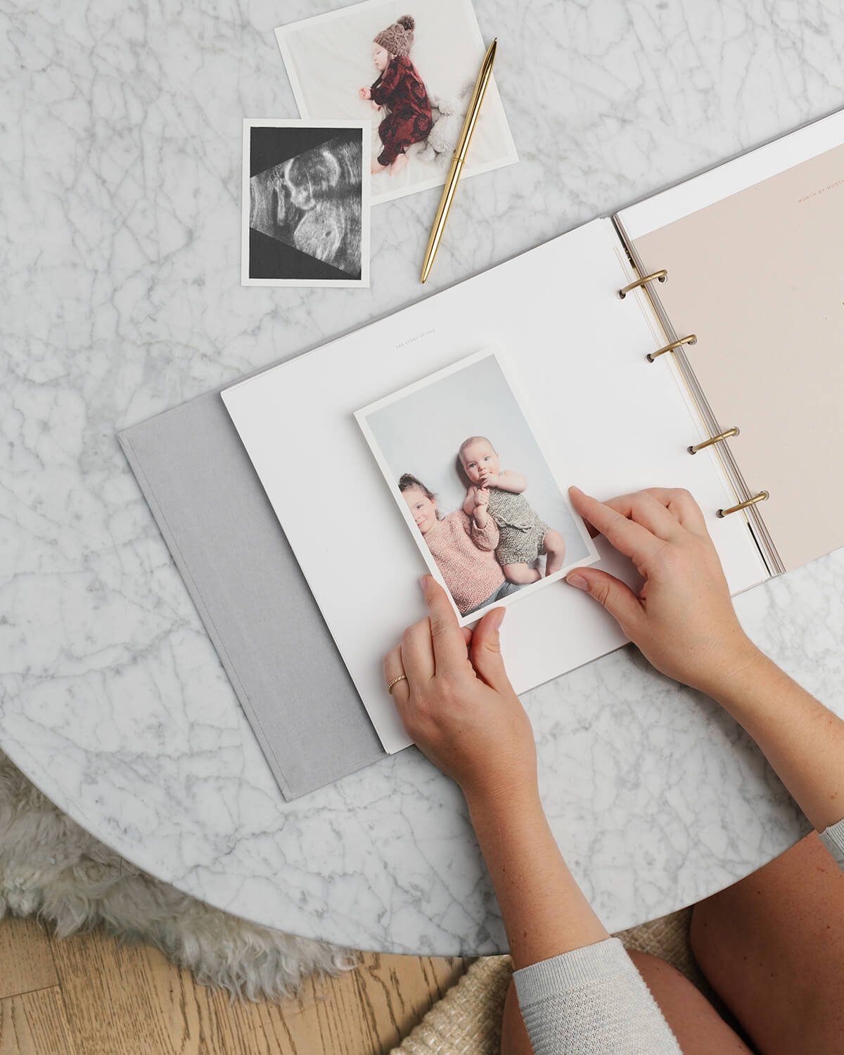 hands placing photo of child in baby book