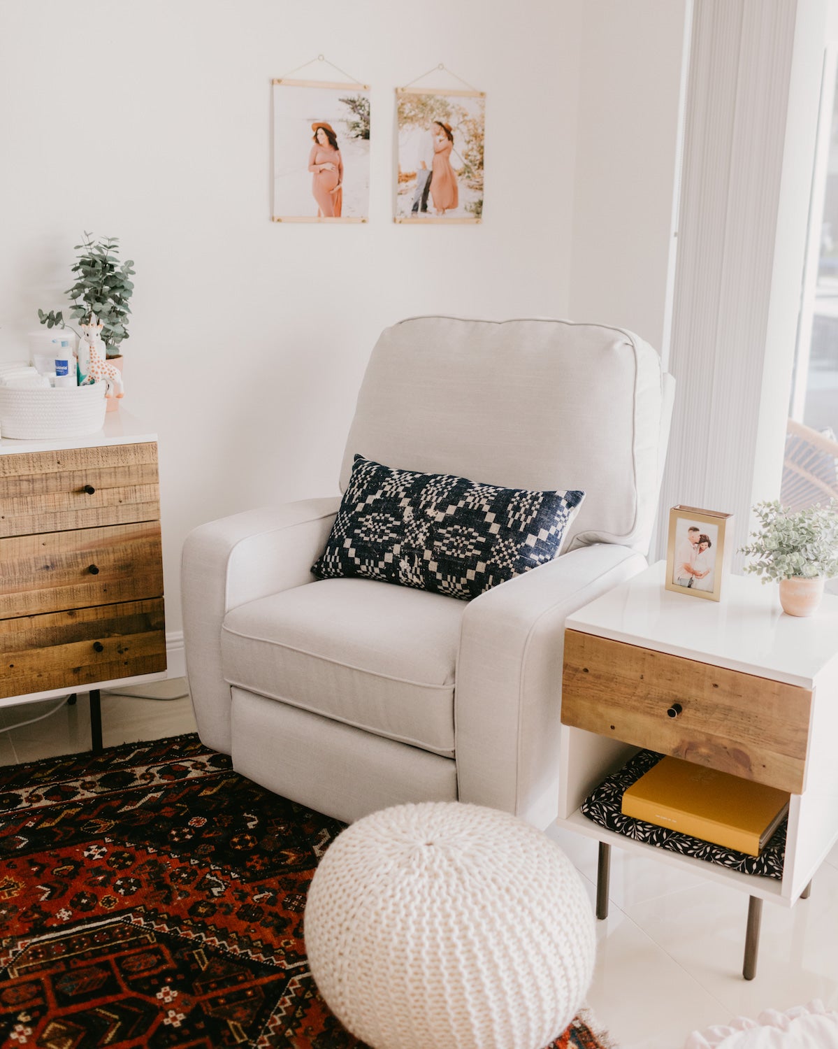 Couch, side table, and pouf with nursery wall decor in background