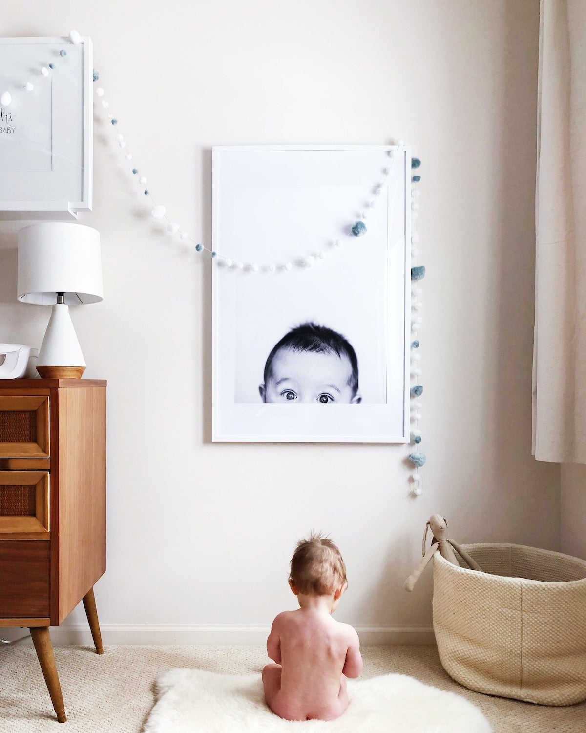 Baby sitting in front of large format print of its own portrait