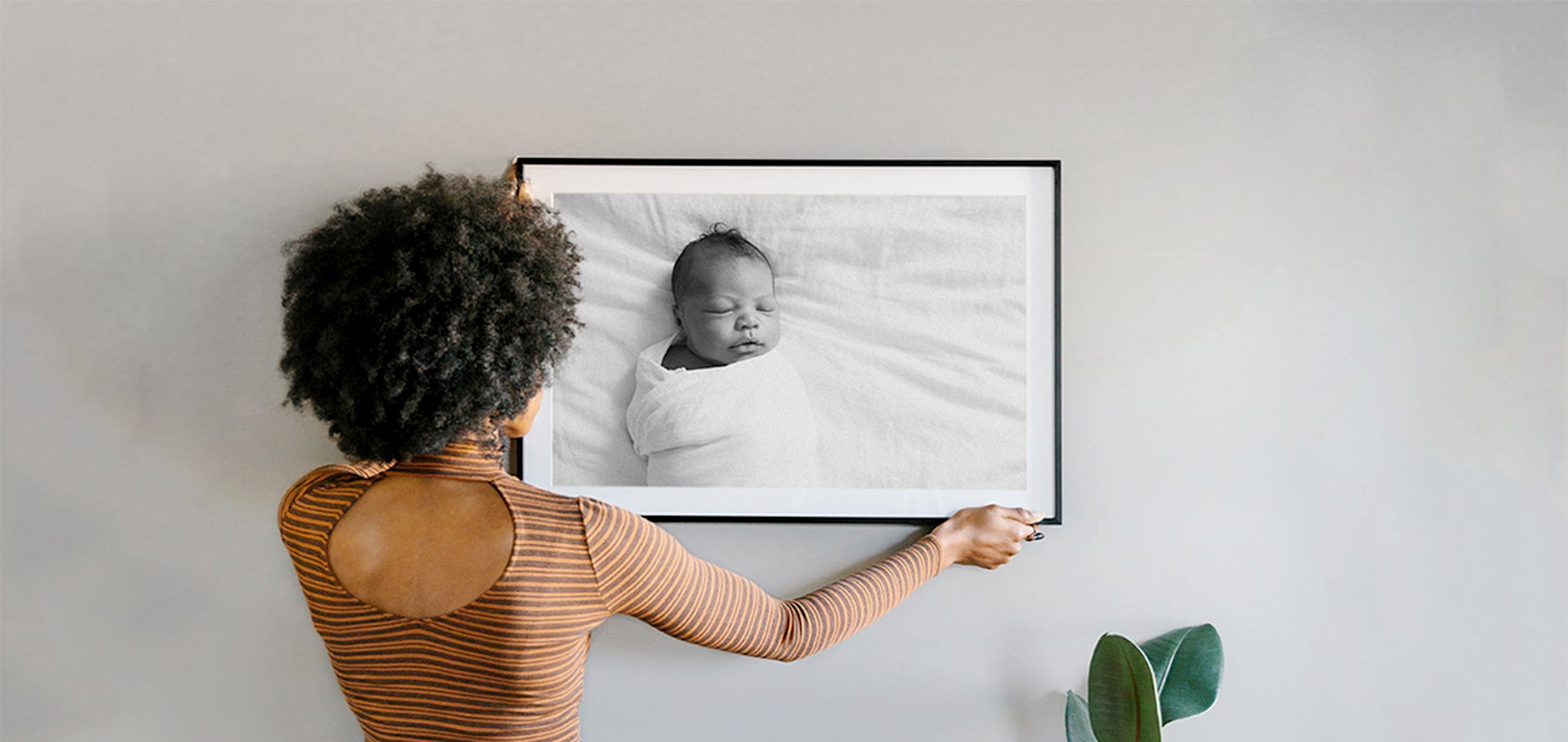 Woman hanging photo of newborn child on wall after choosing from different types of picture frame