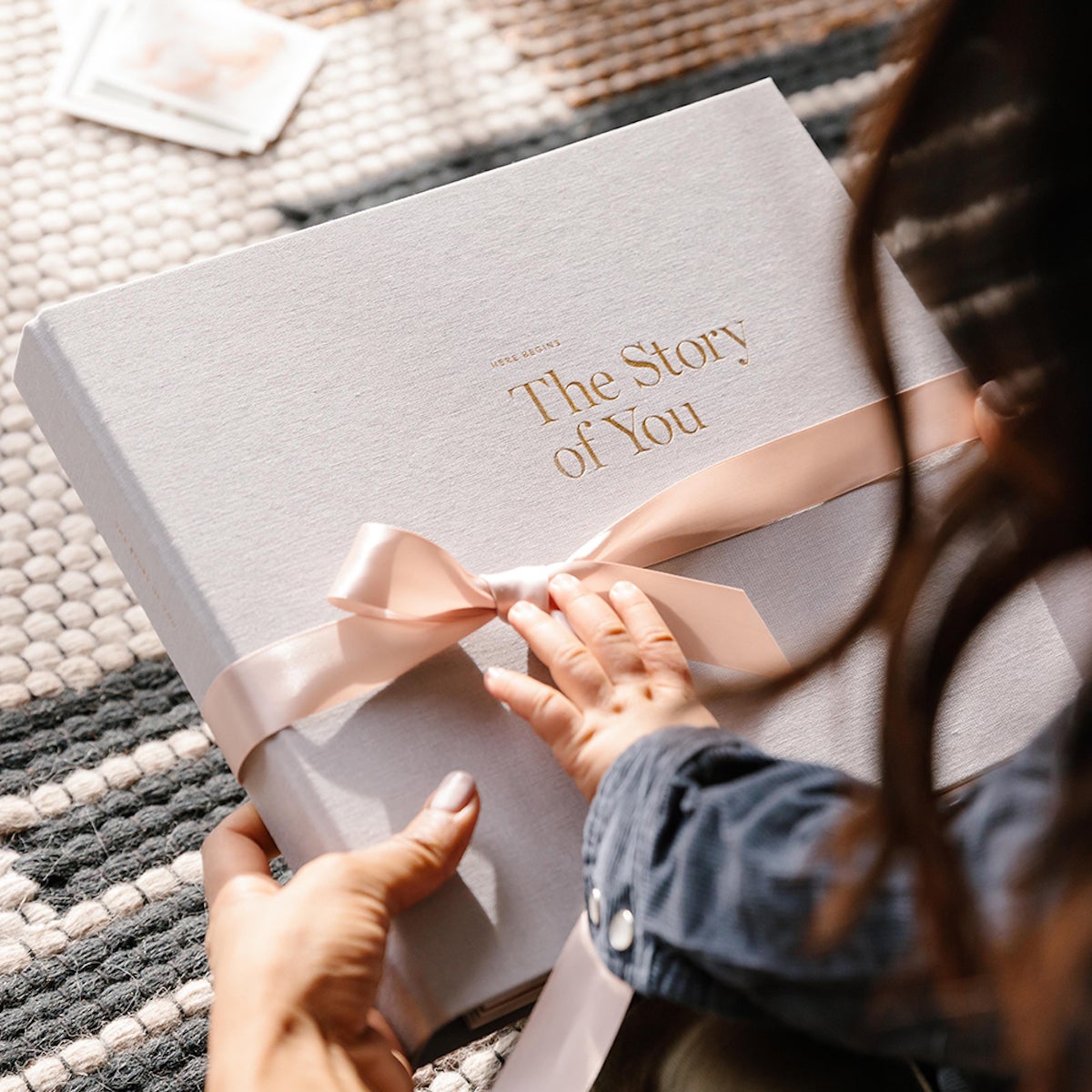 Child's hand on baby book with a bow around it