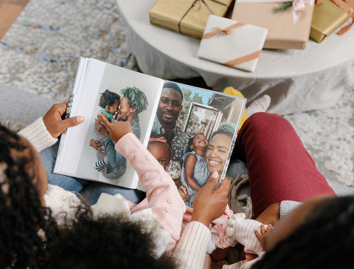 Mother and daughter flipping through pages of hardcover photo book on Christmas morning