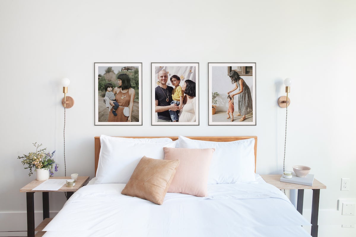 Three large family photos hung up side by side above bed