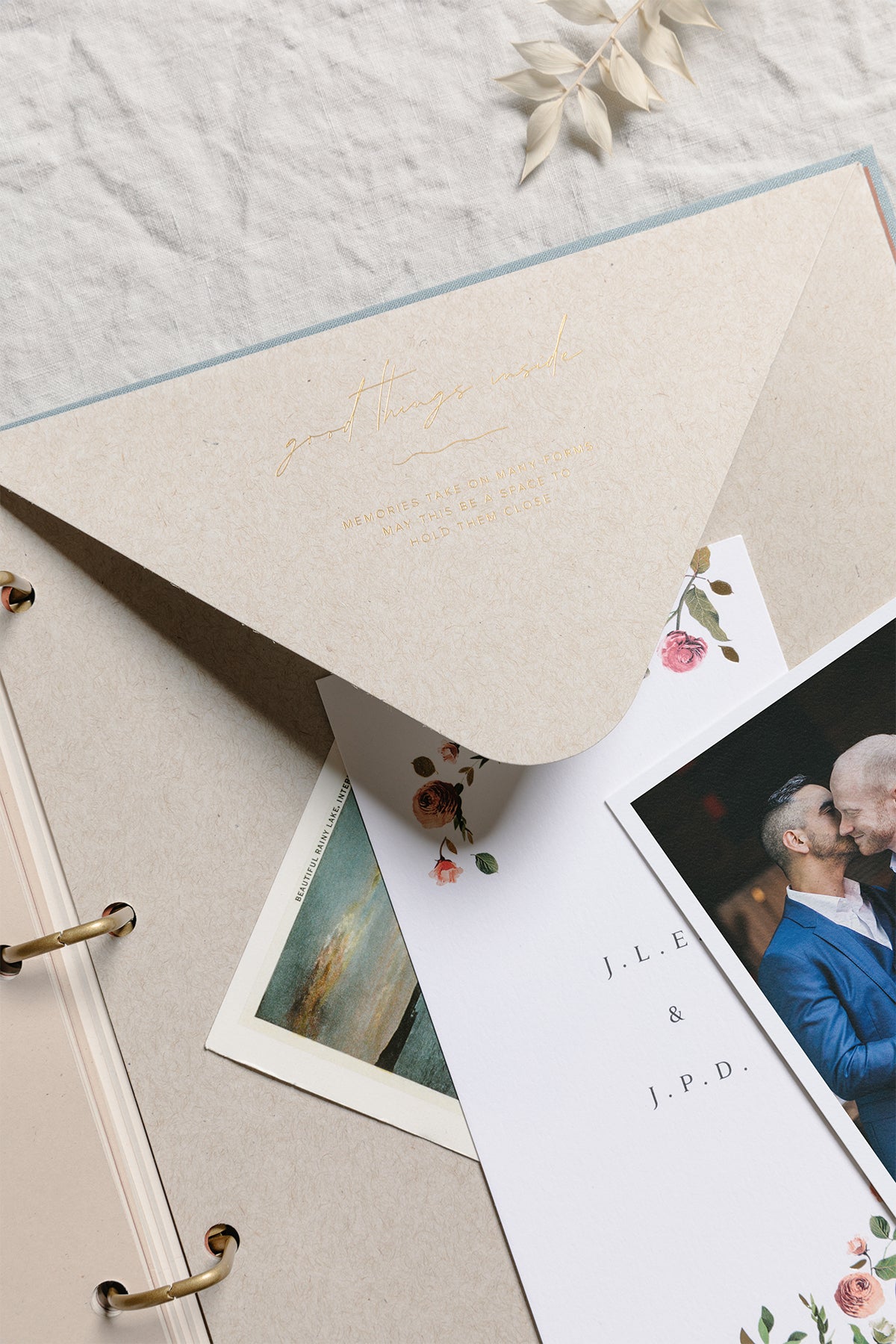 Large envelope inside of scrapbook with wedding invitations on top