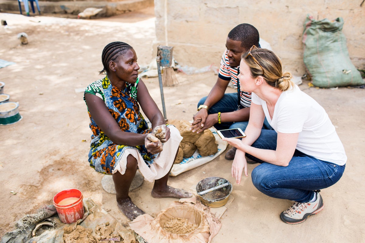 Becky and an Adventure Project volunteer speak with a clean cookstove entrepreneur in Tanzania