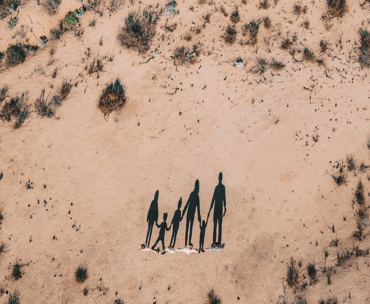 Drone photograph of shadow of family holding hands in the desert
