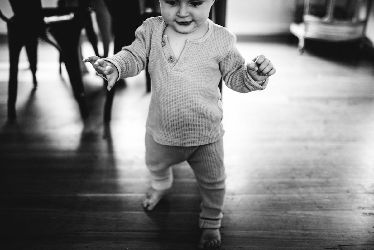 Black and white photo of baby taking first steps
