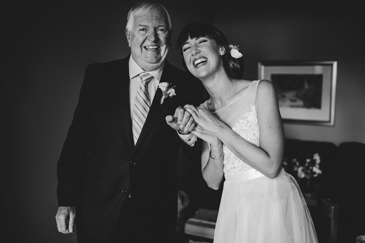 Black and white photo of laughing bride with father