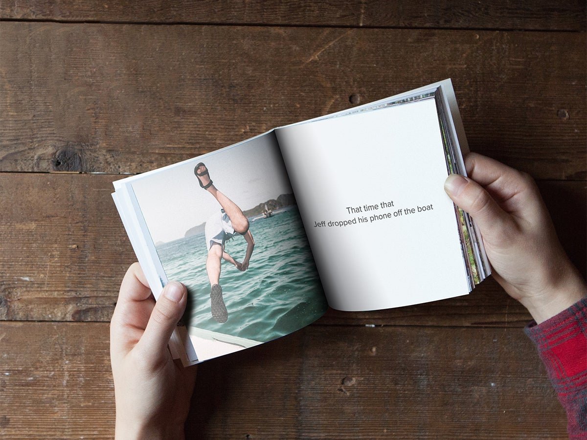 Softcover photo book opened up to a picture of a man diving into water off of a boat