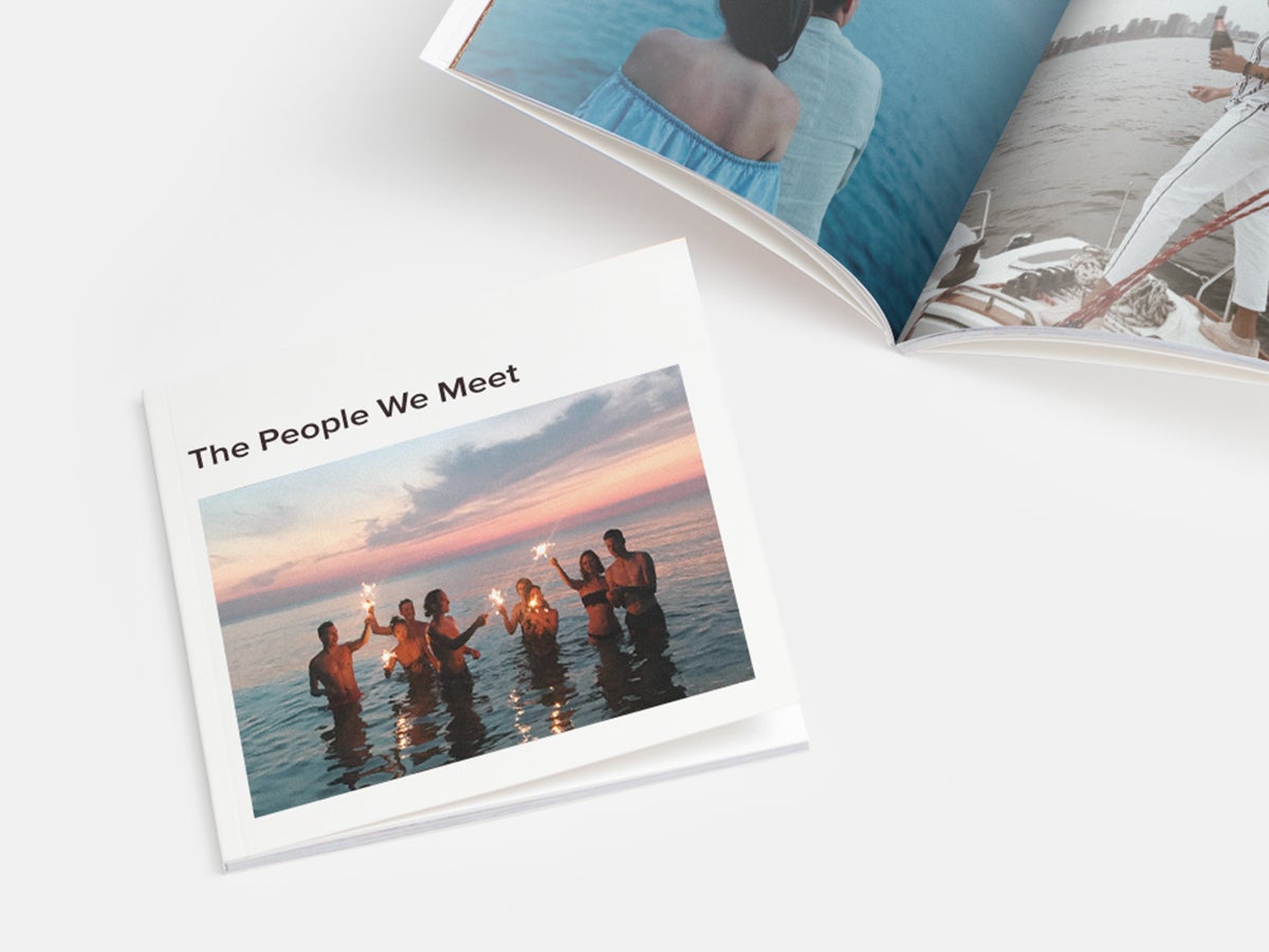 Softcover photo book titled the people we meet with an image of a group of people standing in the ocean