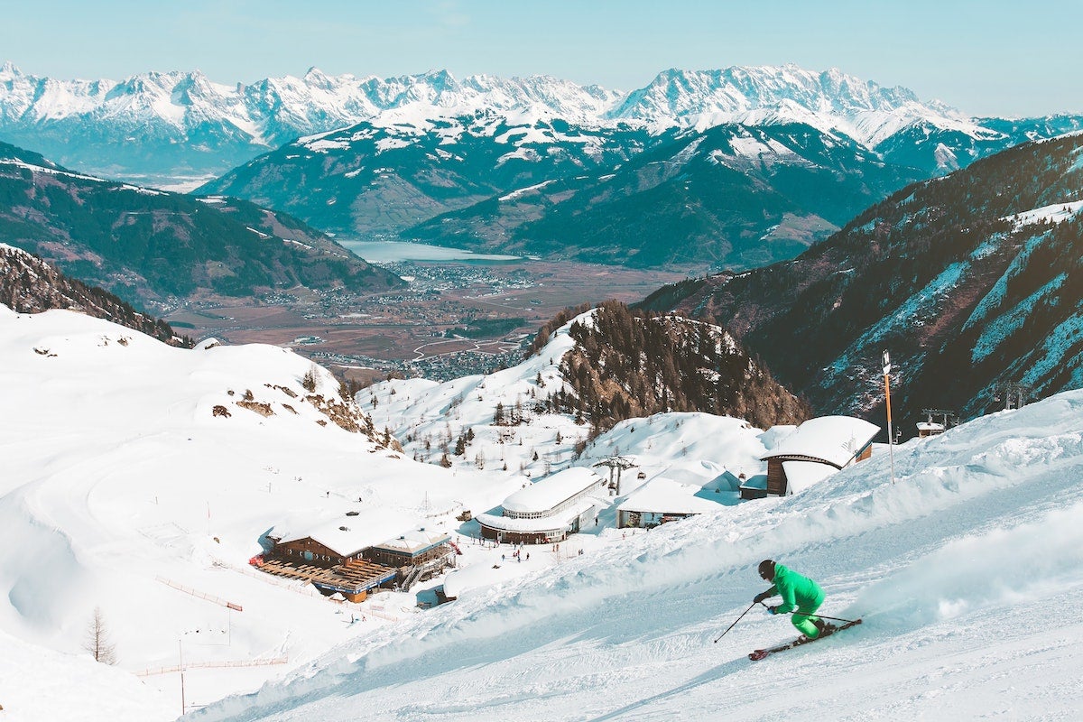 Skier riding downhill with snowy peaks in the background