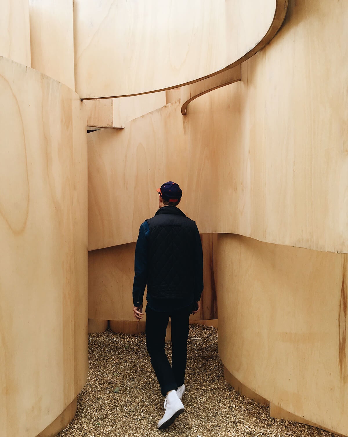 Man-walking down well-lit path formed by two curving walls