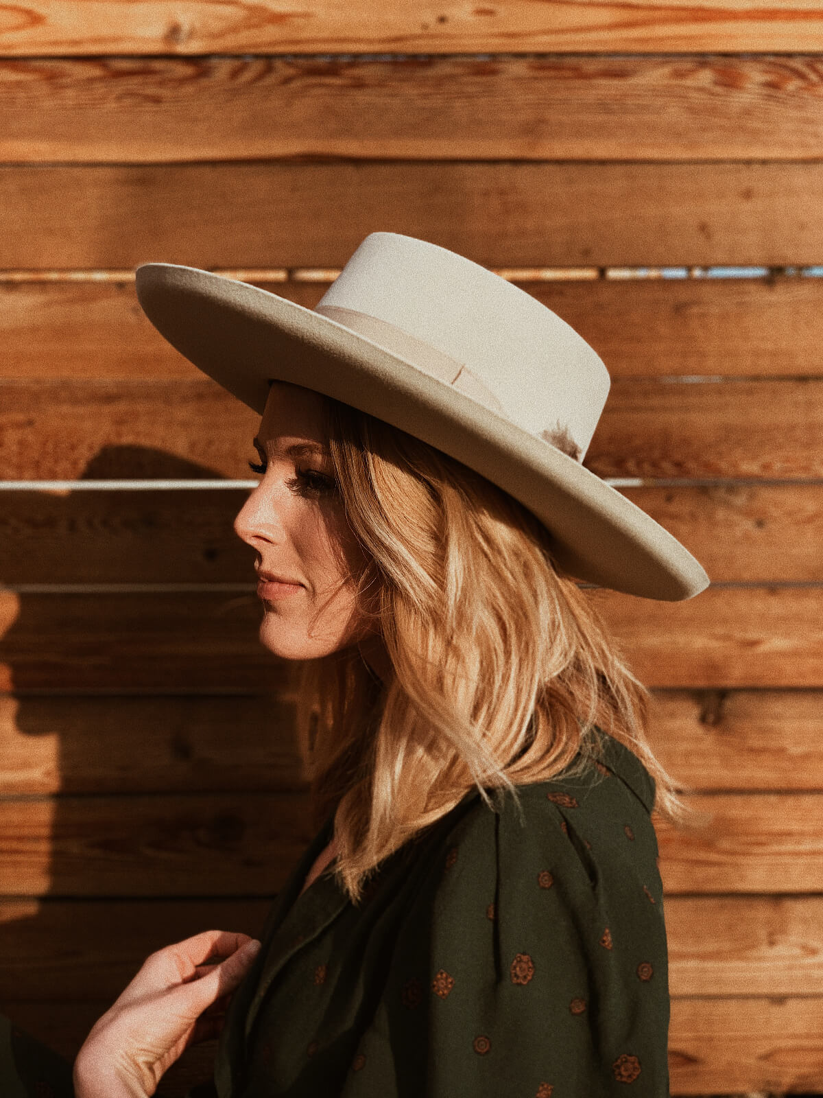 Portrait of young blond woman turned to the side and wearing a large-brimmed derby hat