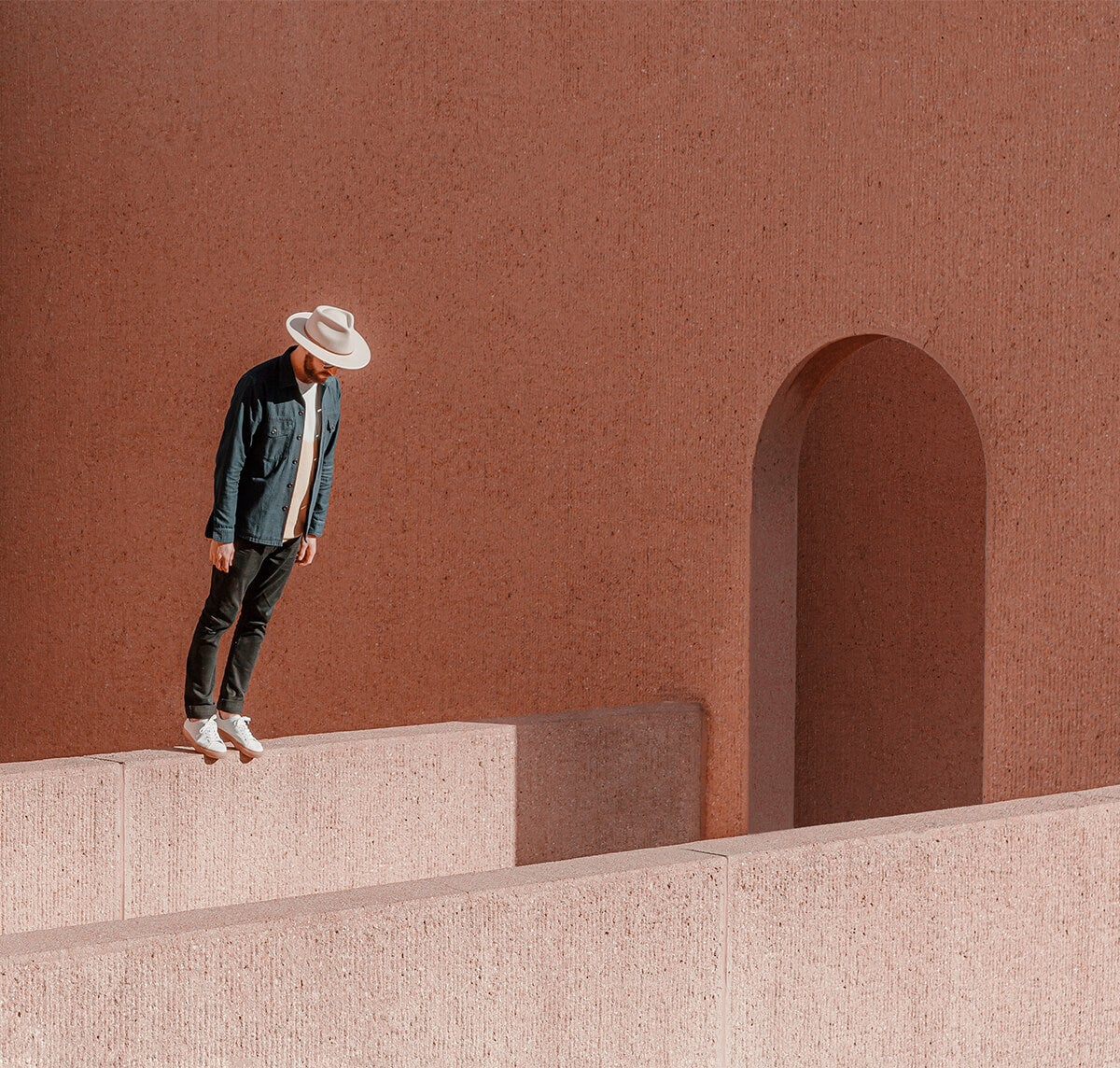 Optical illusion of man standing on ledge and leaning over