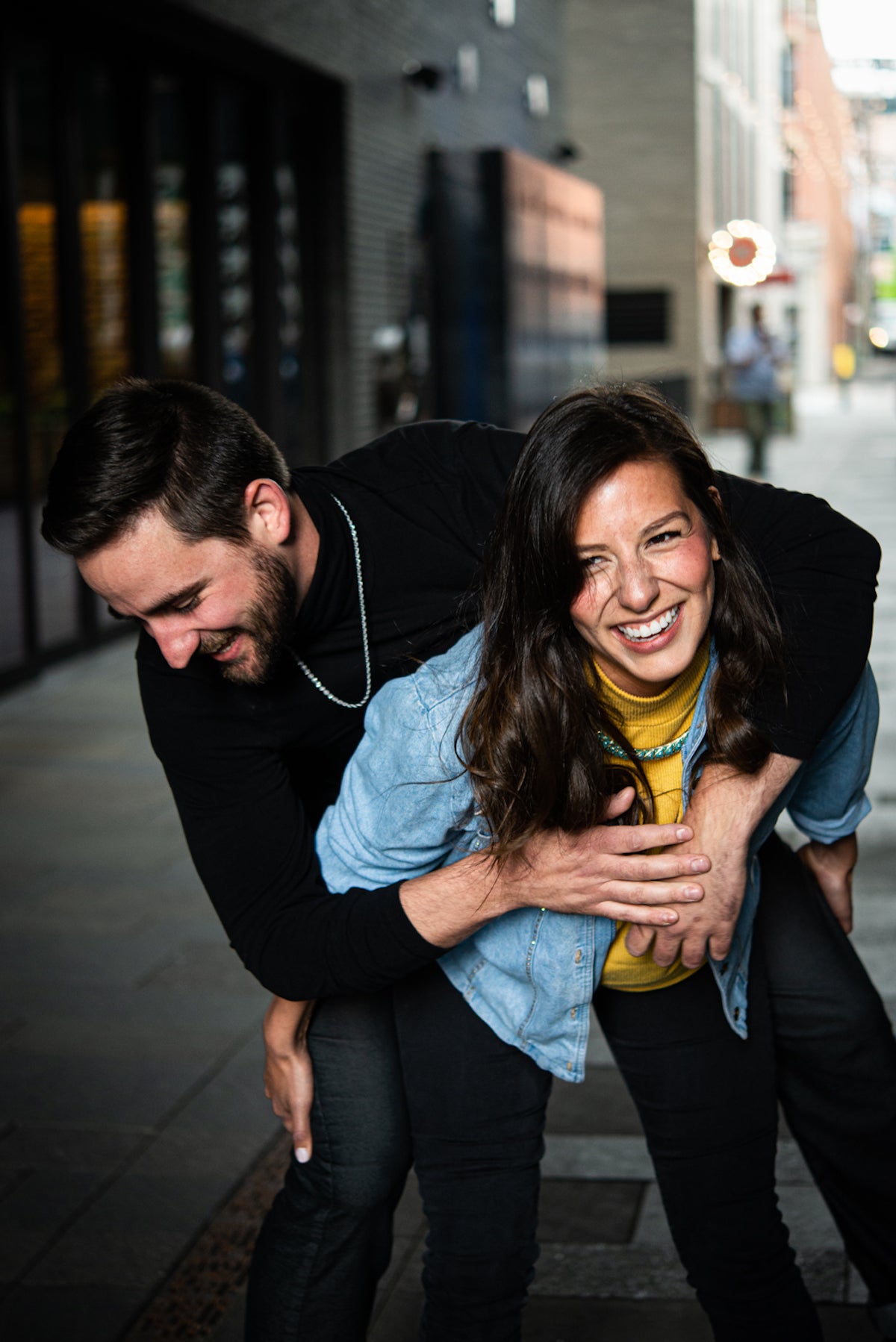 Young woman laughing as she tries to give boyfriend a piggyback ride