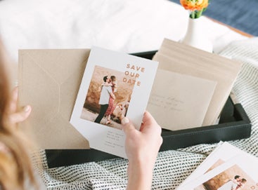 woman putting save the date card in envelope
