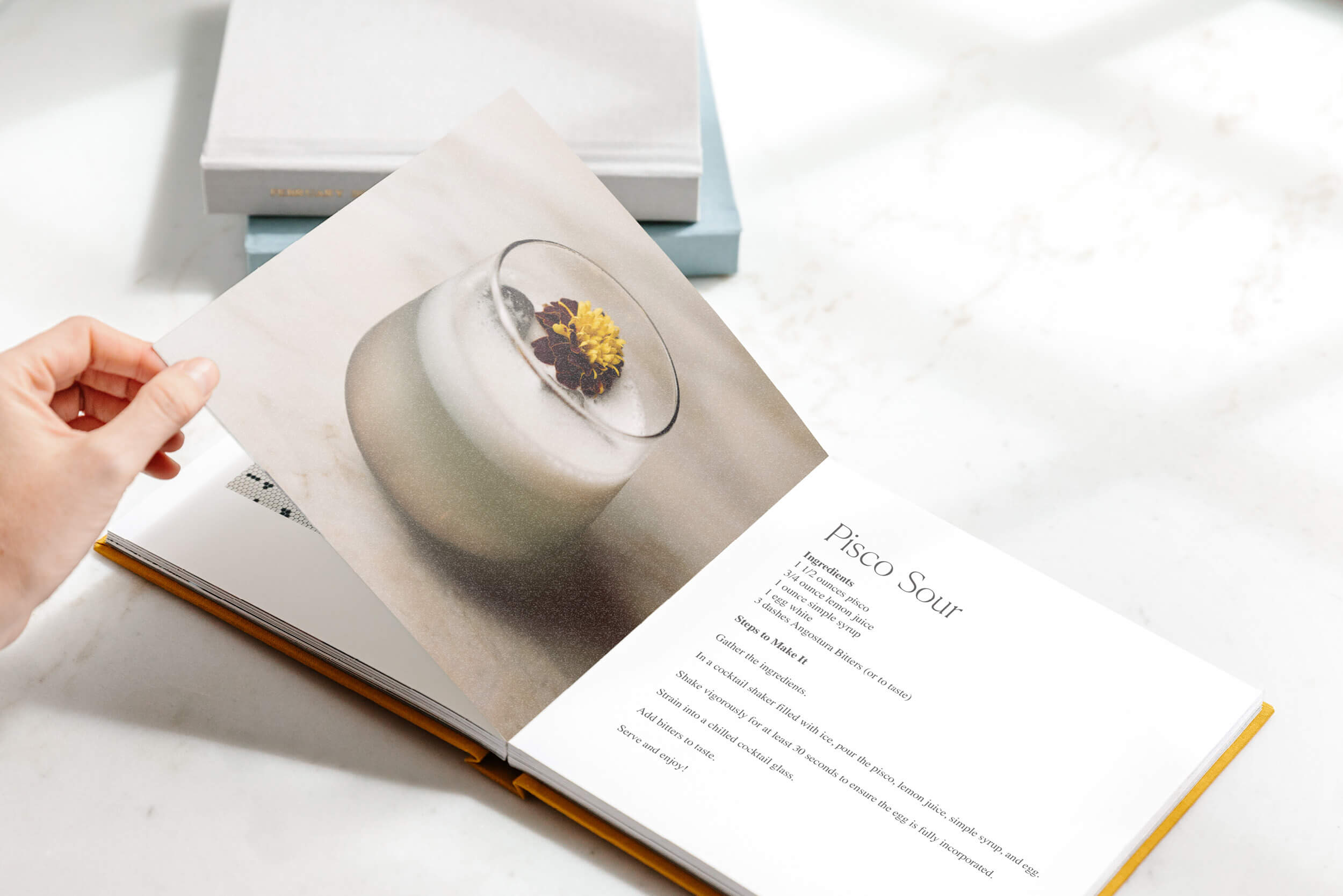 Cocktail book opened to recipe for a pisco sour