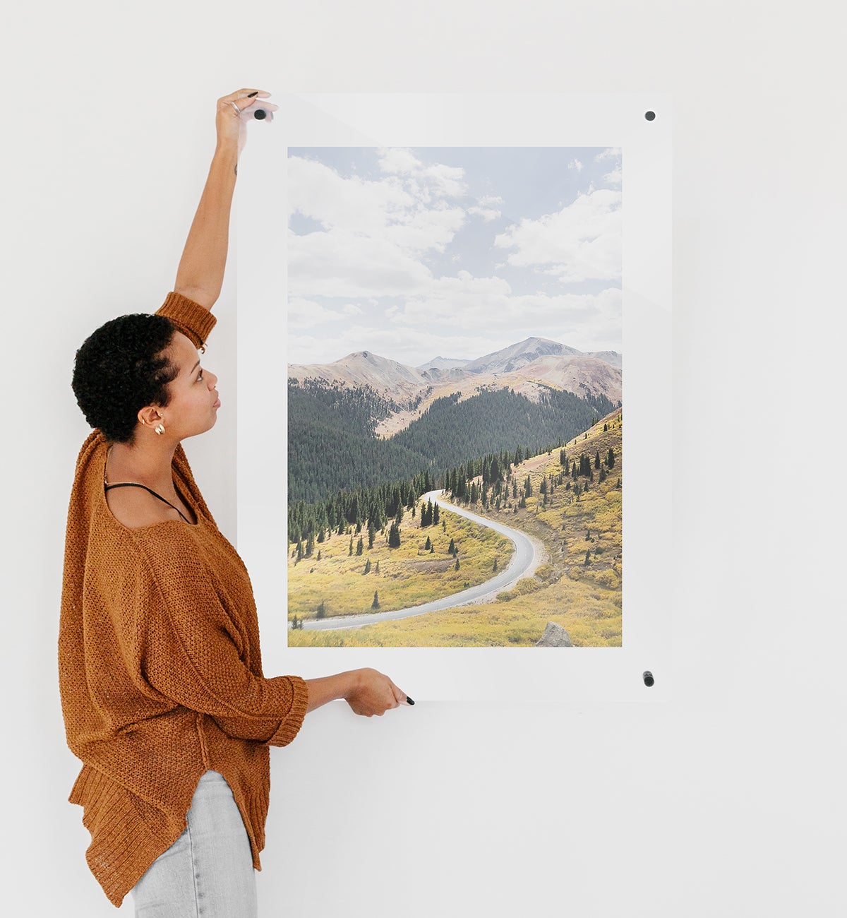 Woman hanging up floating frame featuring mountain landscape