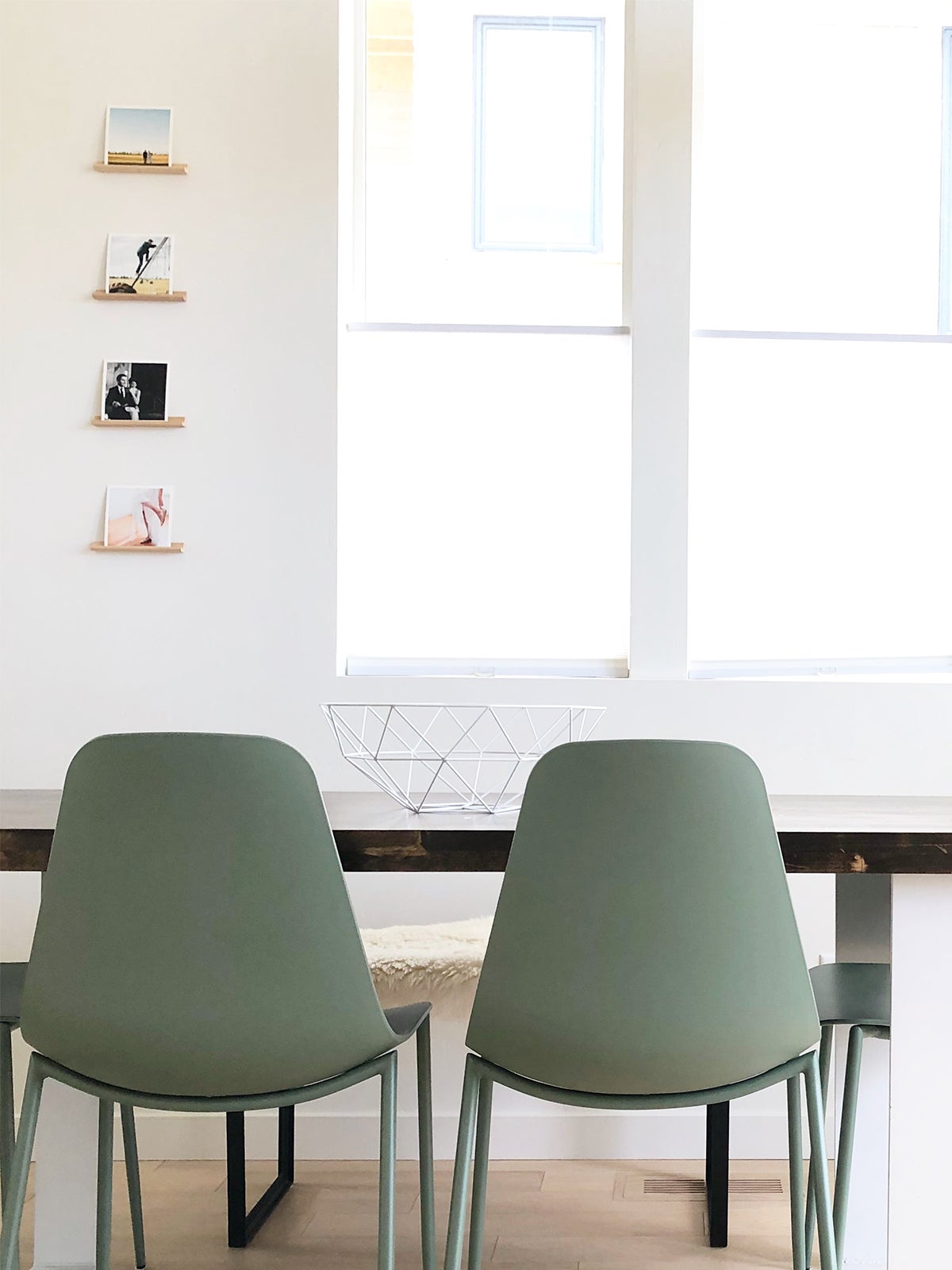 Dining room with stacked wooden photo ledges on wall holding prints