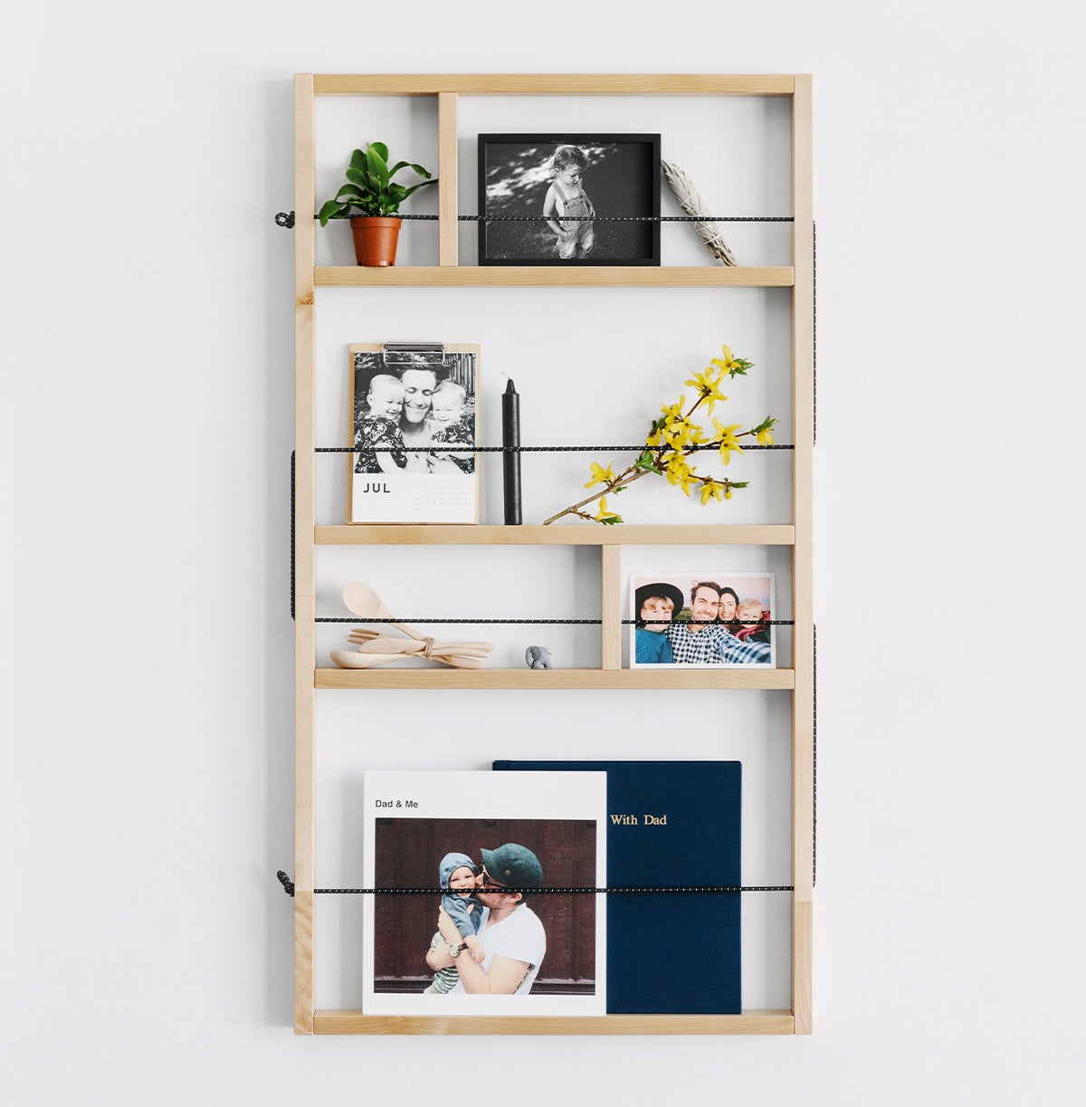 Wall-mounted shelf filled with photo-prints and other decor