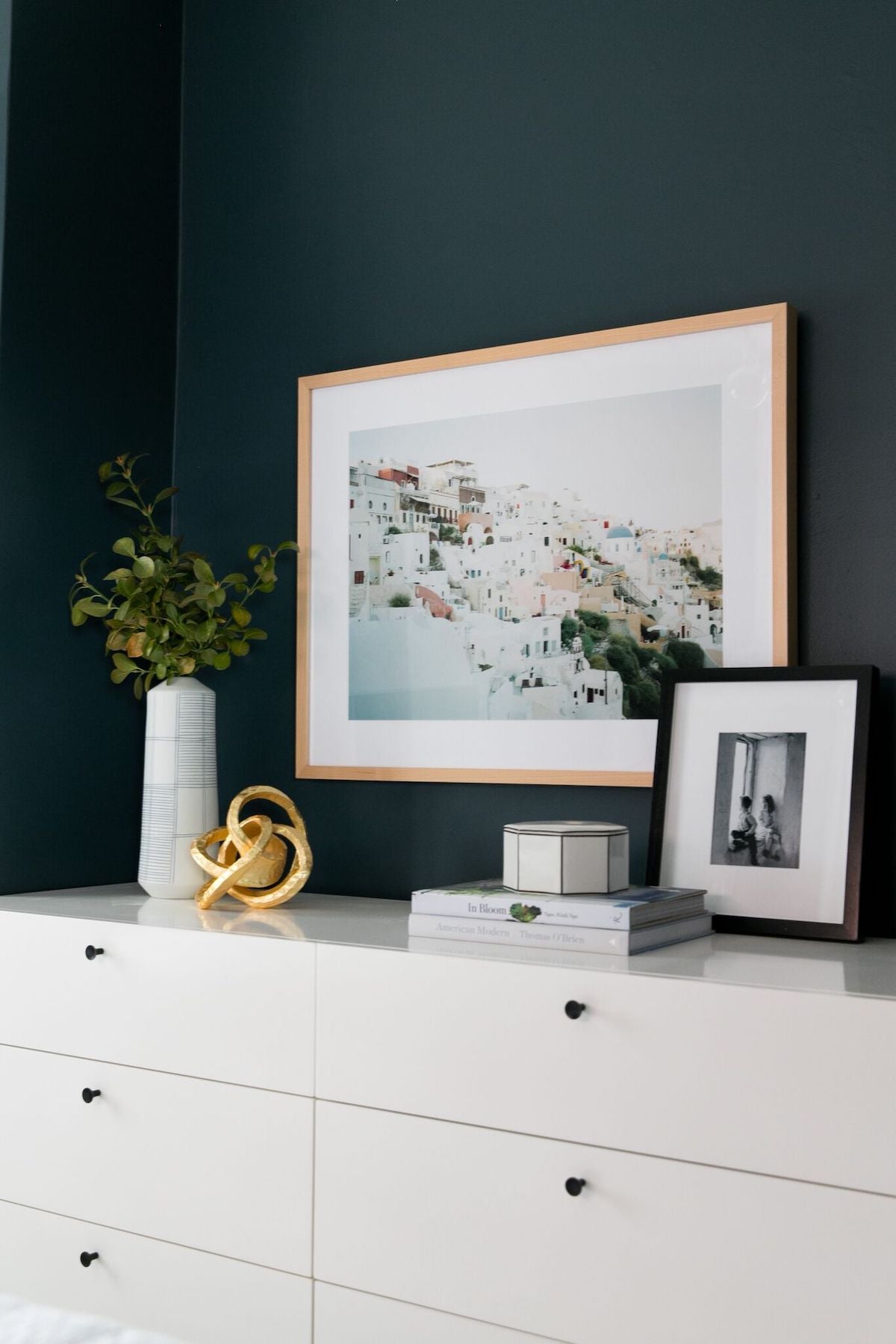 White dresser with small decor items on top and picture hanging above