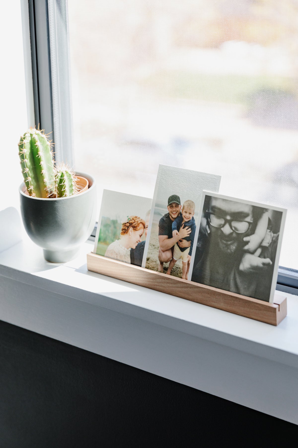 Photo ledge with prints on windowsill next to cactus plant