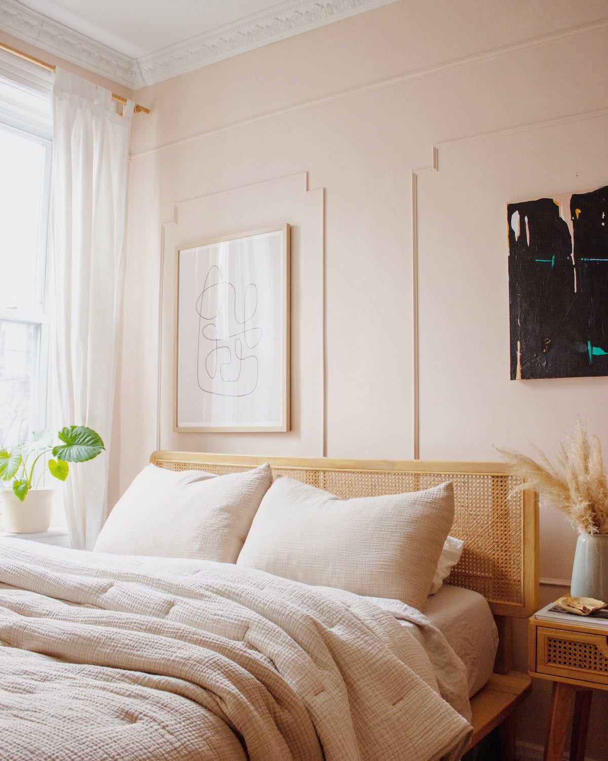 Bedroom decorated in all blush with small plant in corner