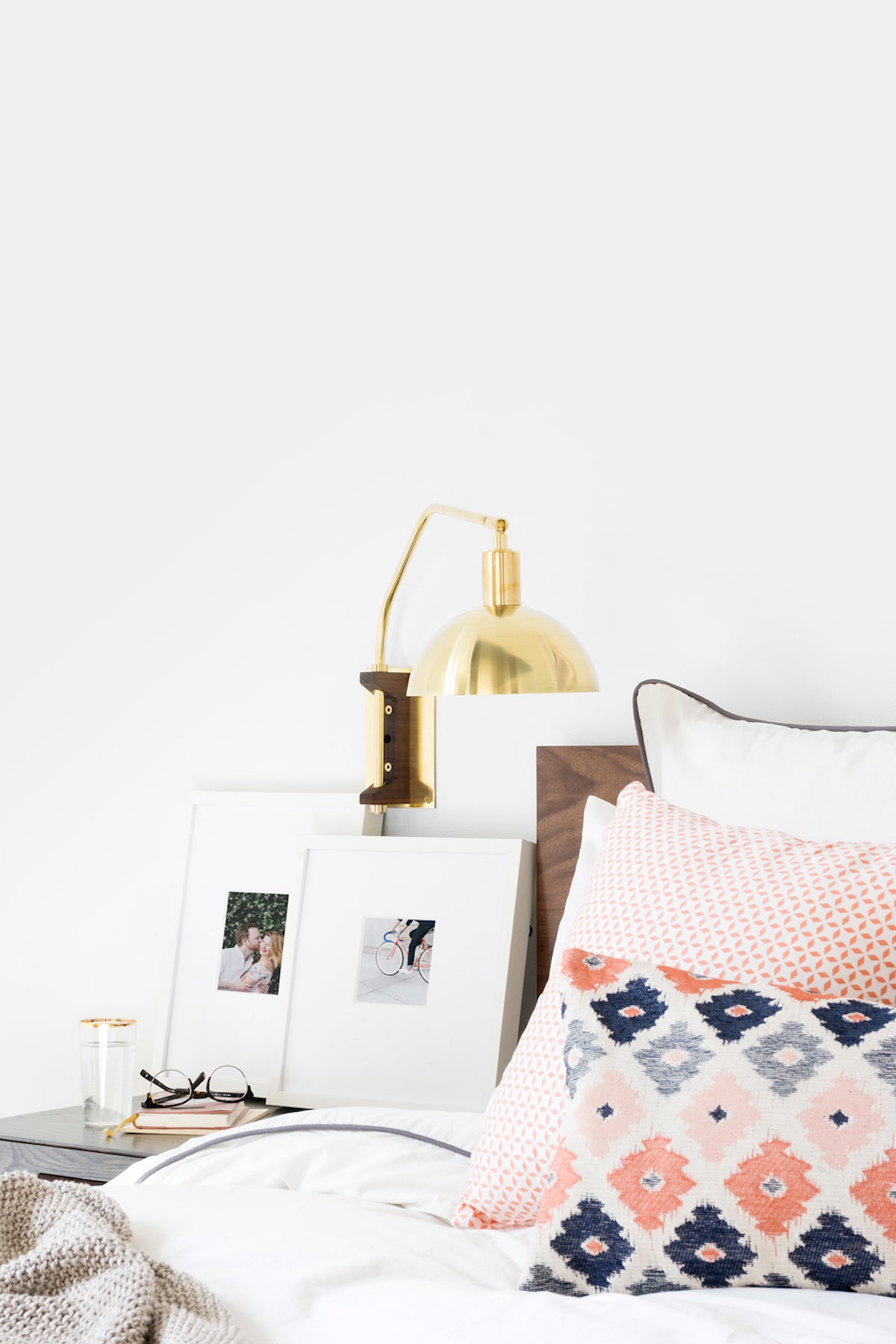 Two white frames on nightstand resting in layered fashion against the wall
