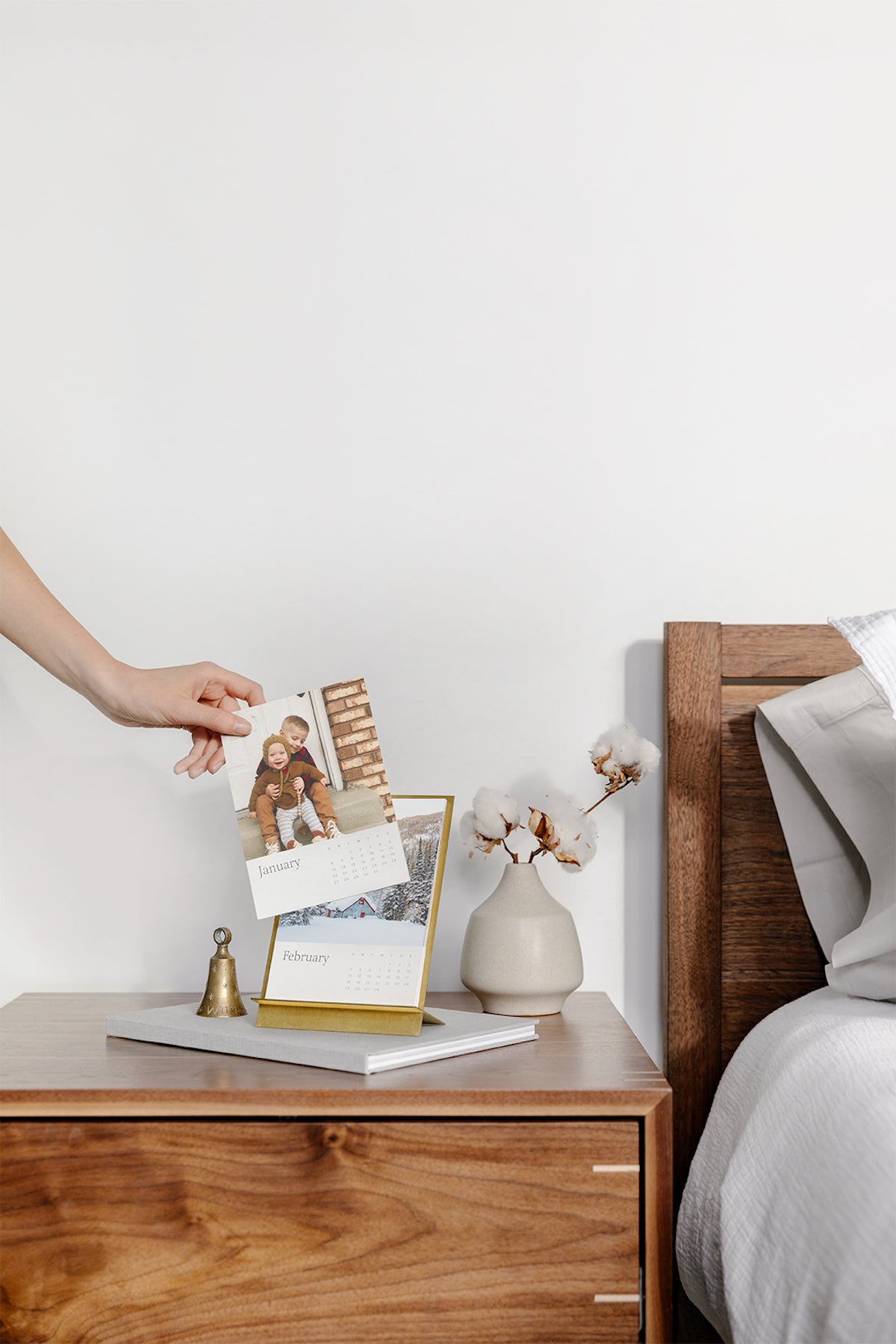 Woman's hand changing month on nightstand calendar