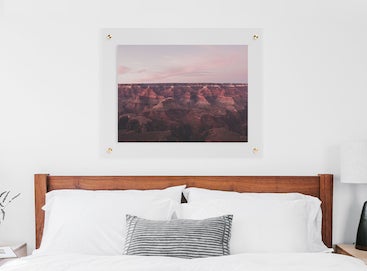 large floating frame hanging above bed with white bedding