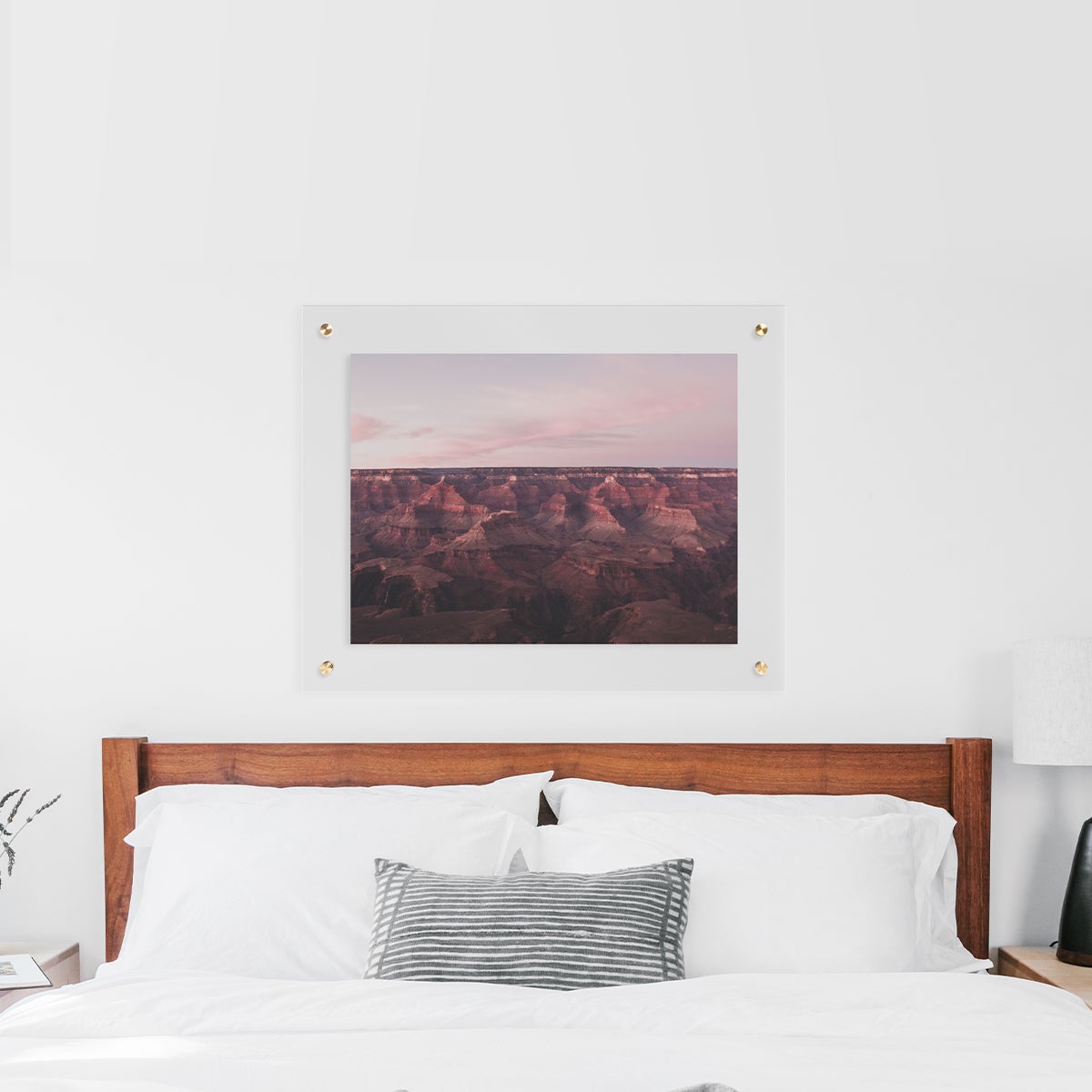 Floating frame with desert landscape hanging above white bed