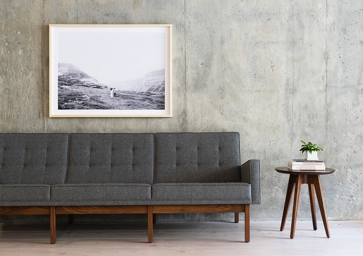 Large framed photo of couple in desert landscape hung above gray couch