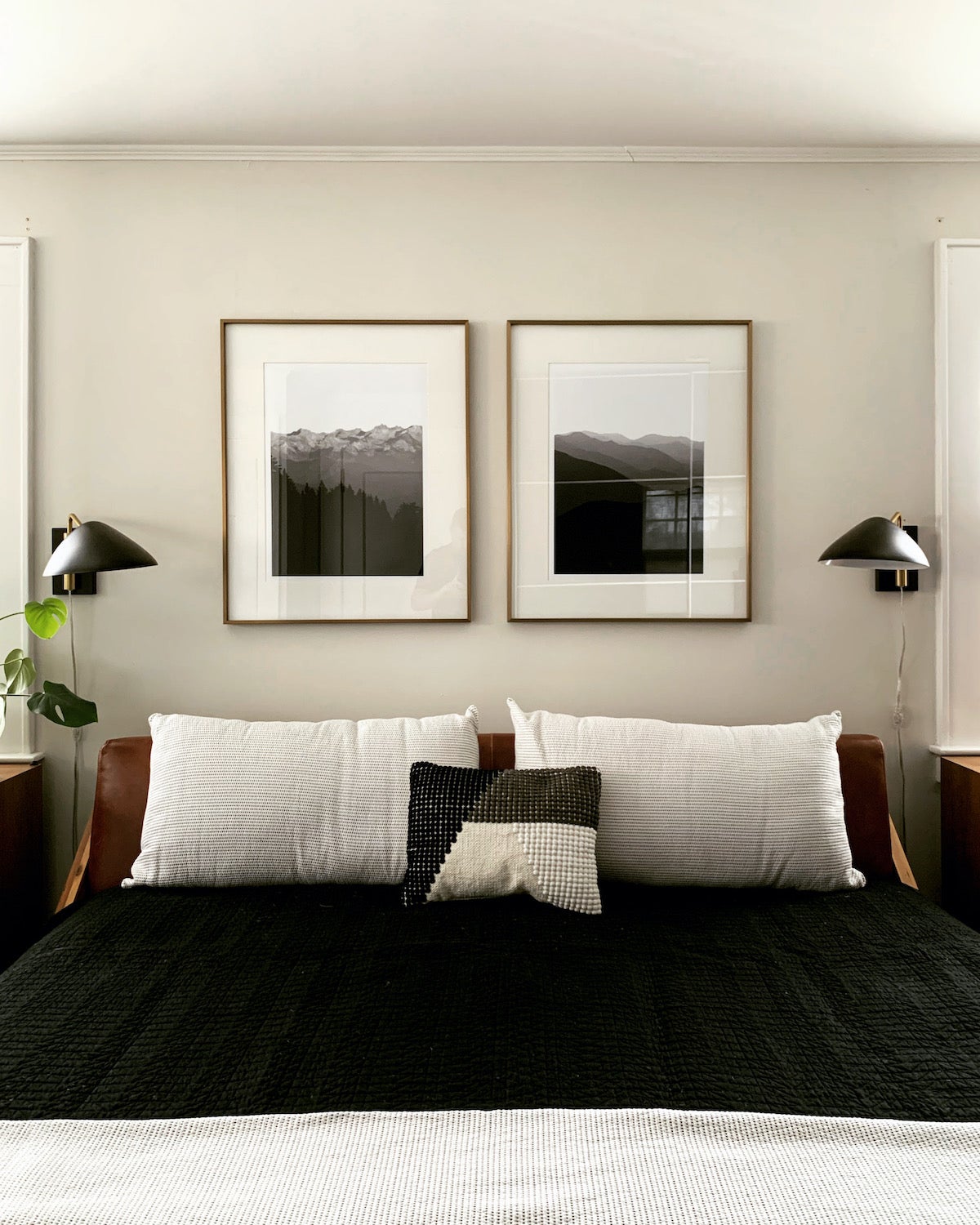 Two framed Artifact Uprising Large Format prints hung above bed featuring black-and-white images of mountainscapes