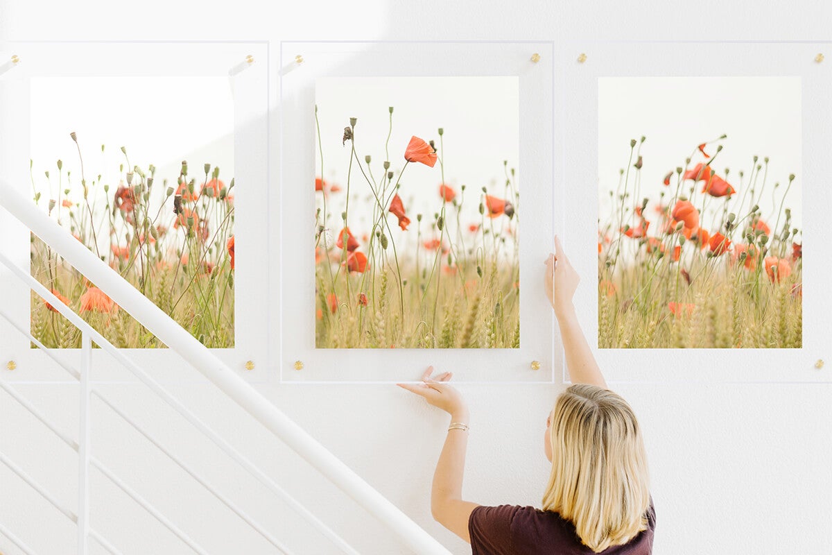 Woman hanging up floating frame to complete triptych gallery wall