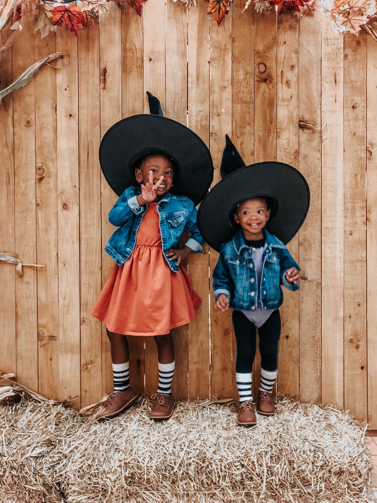 Photo of little girls in Halloween costumes posing for a photo in front of wooden fence
