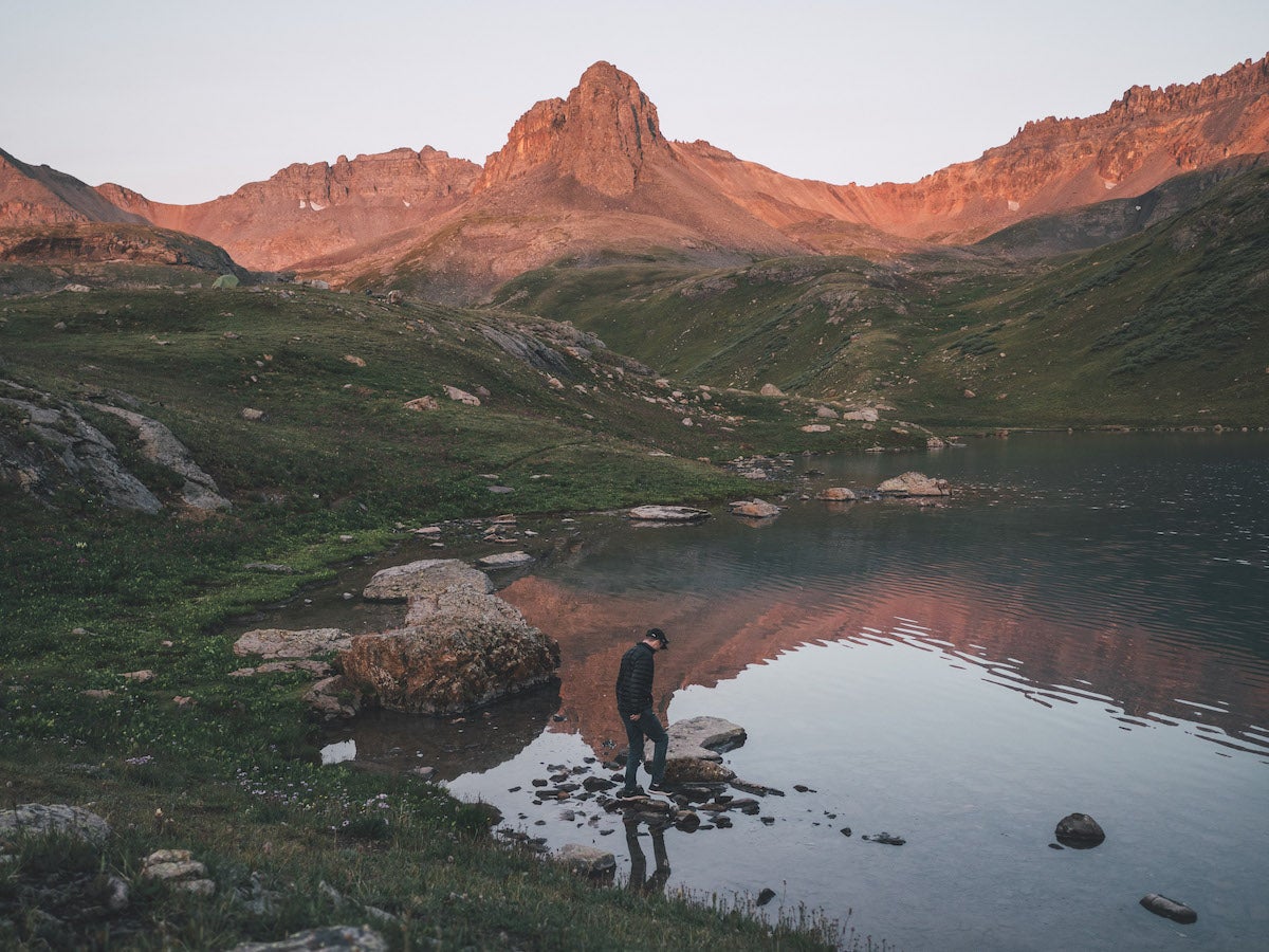 Man at the edge of an alpine lake at golden hour