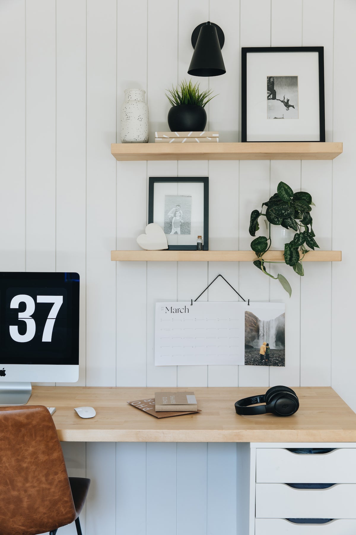 Wall-mounted shelf filled with photo-prints and other decor