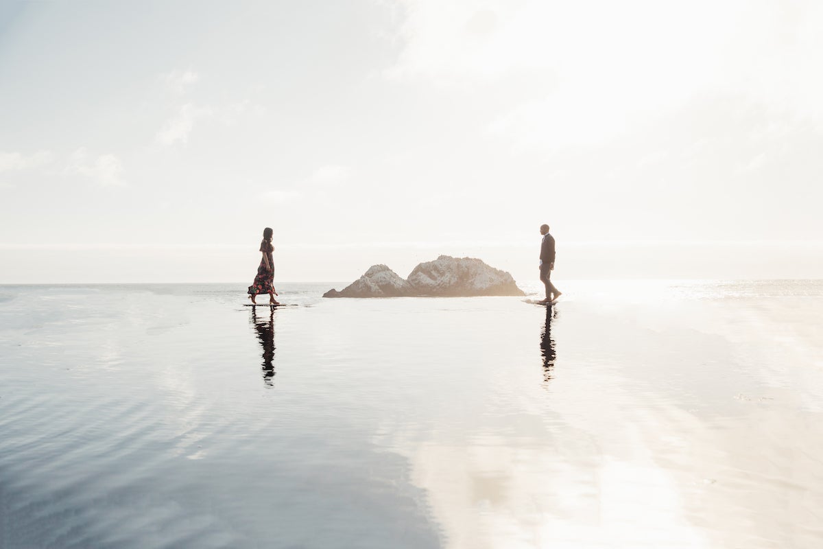 Couple walking toward each other in shallow coastal waters