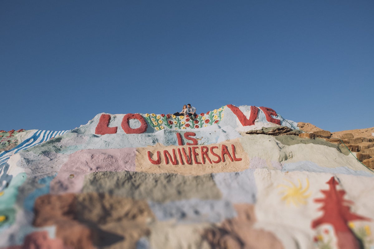 Couple atop hill with graffiti of love is universal