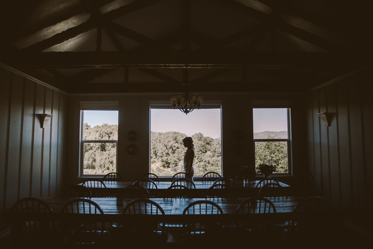 Silhouette of bride standing in front of large windows