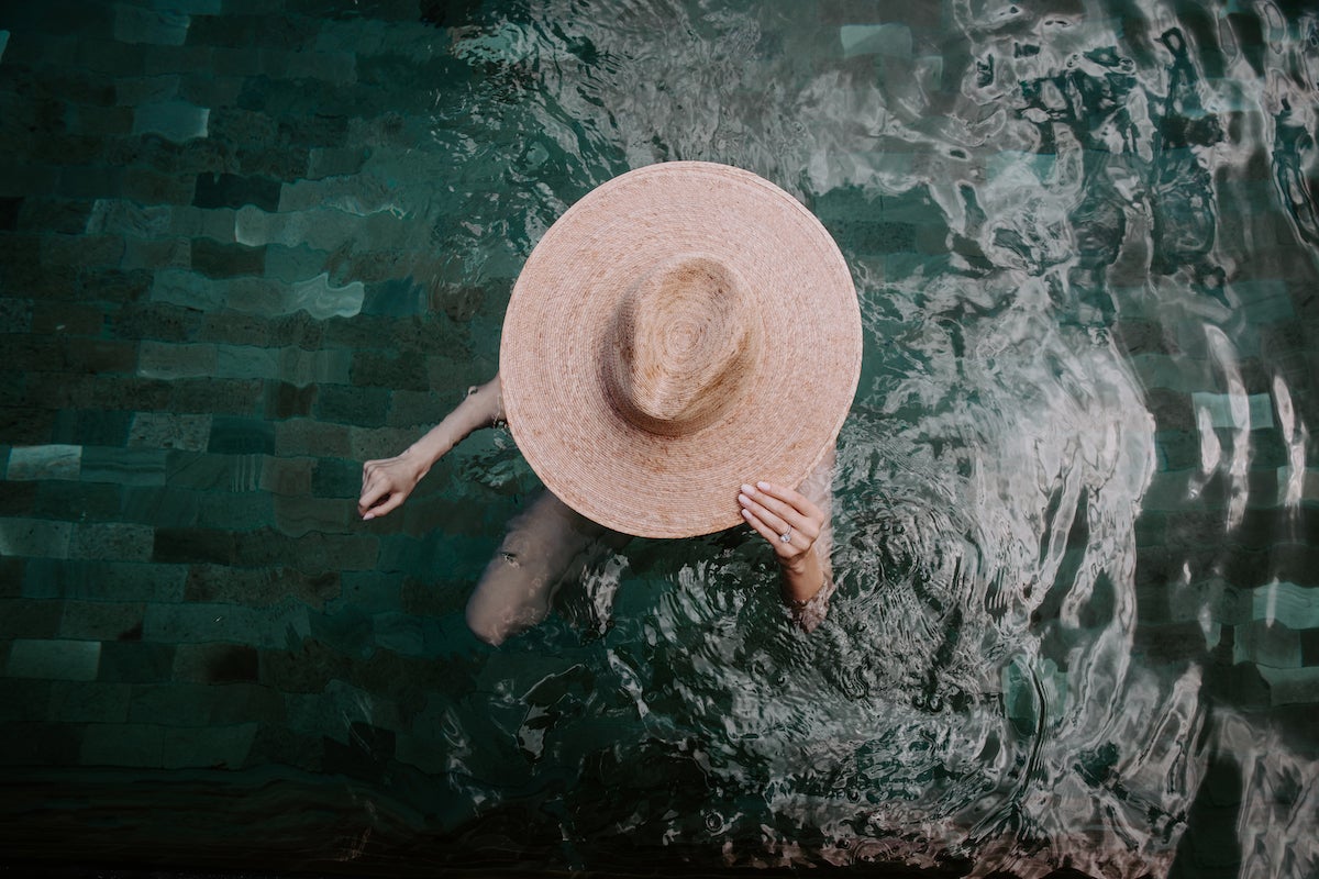 Overhead shot of bride in pool in large sunhat