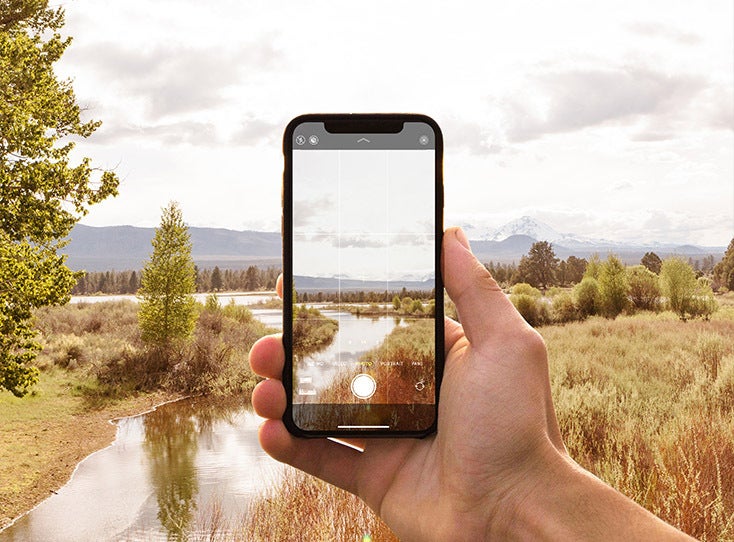 iphone taking photo of scenic wilderness with mountain backdrop