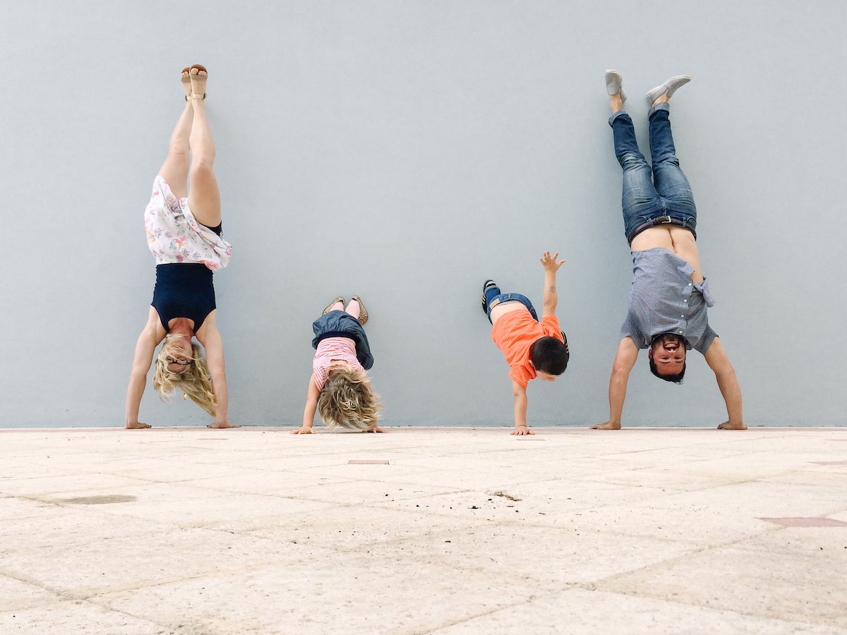 Family upside down doing handstands against wall