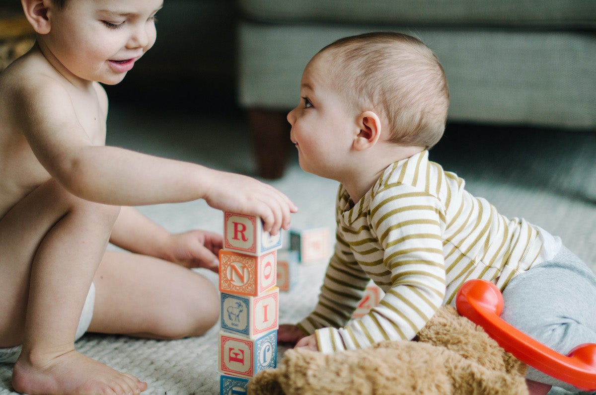 Toddler and baby playing with building blocks
