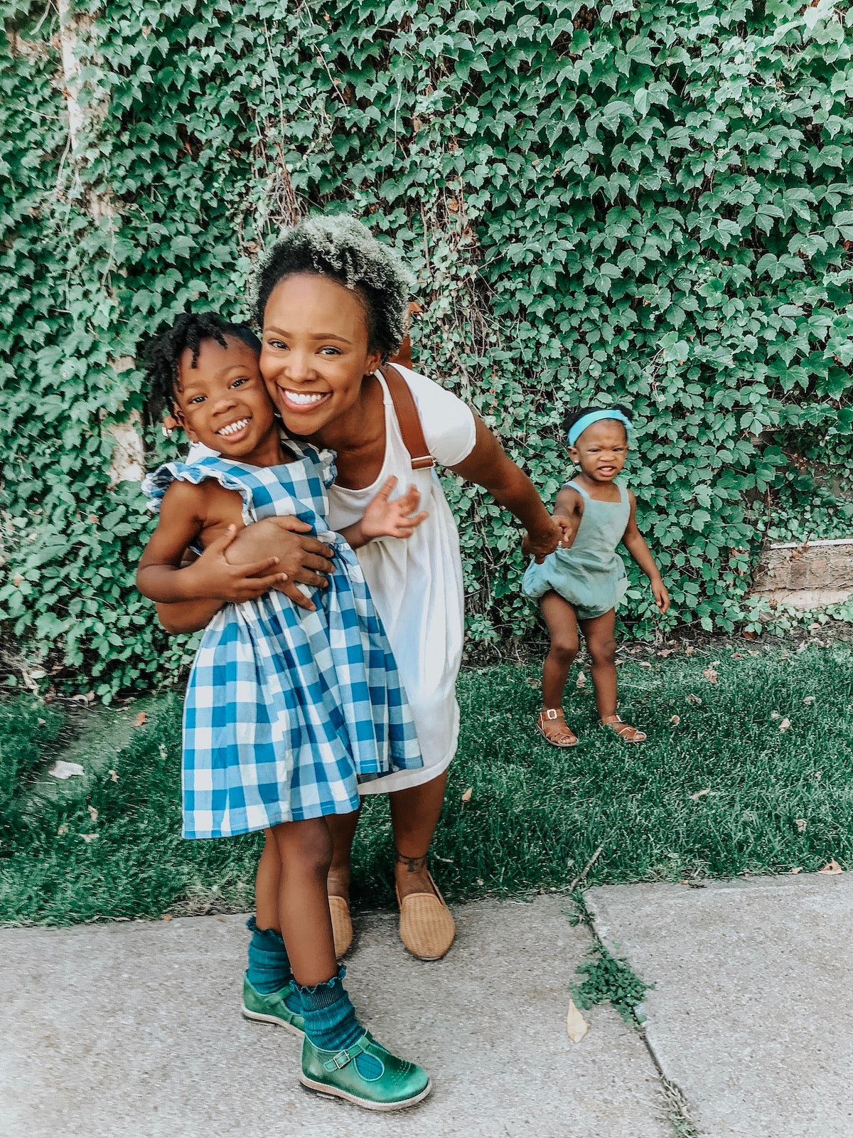 Mother with children in front of wall overgrown with vines