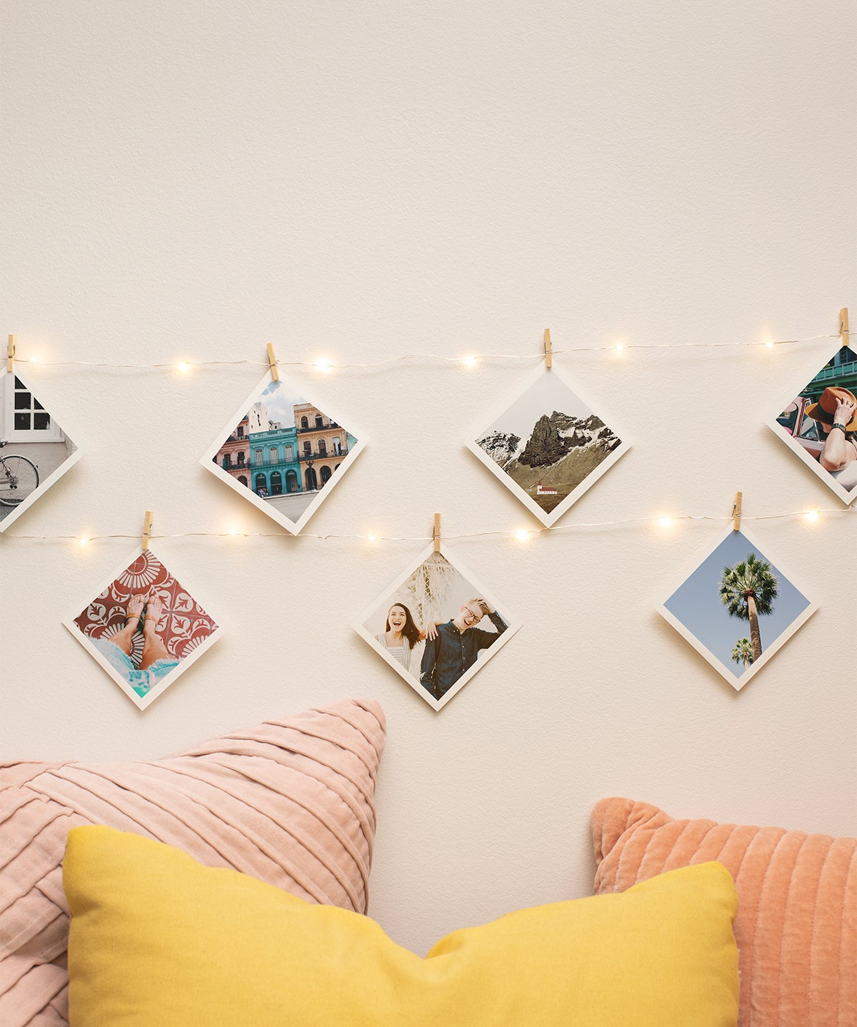 Photo prints hanging from string lights on wall
