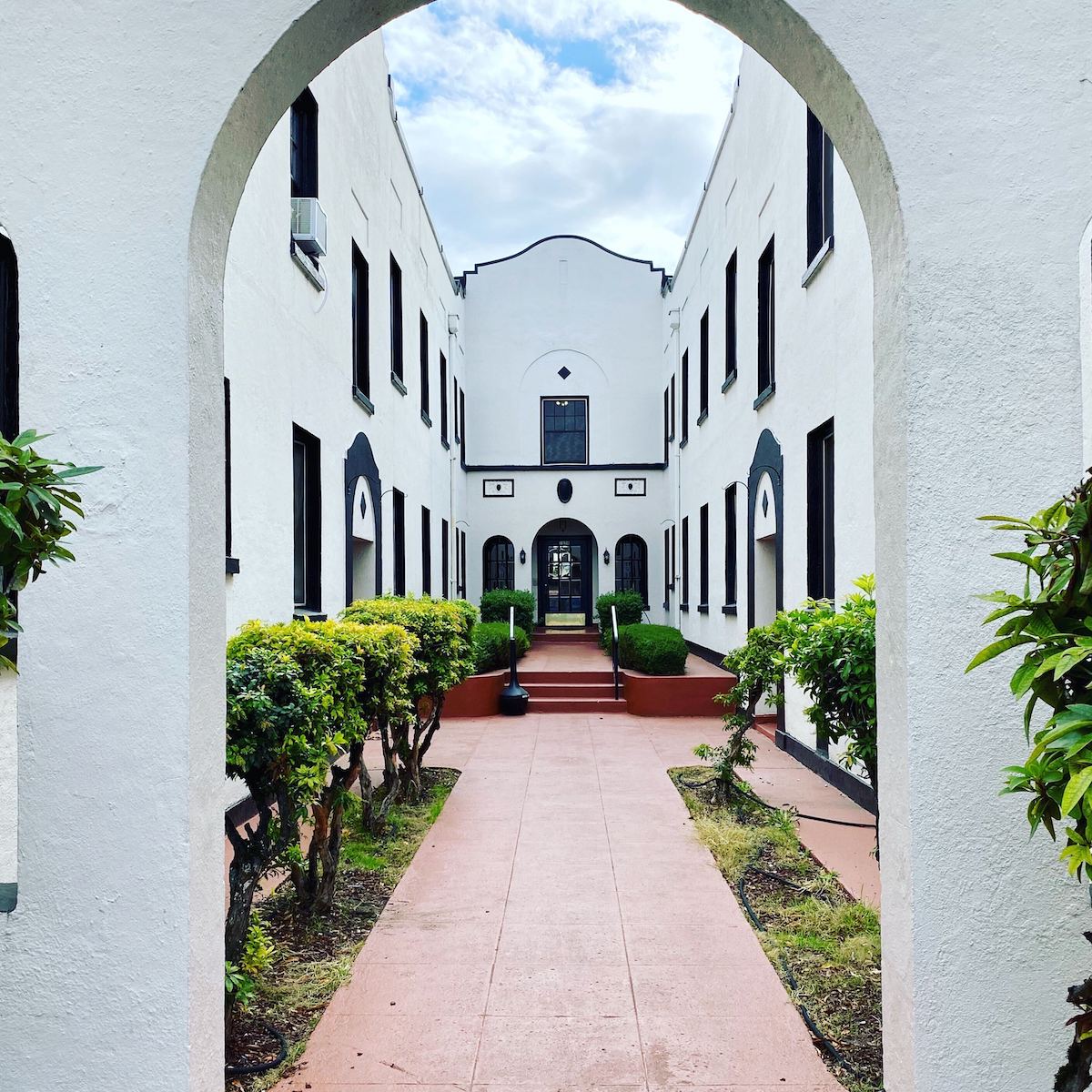 A photo of an archway of a white building in the foreground with the rest of the building shown in the background