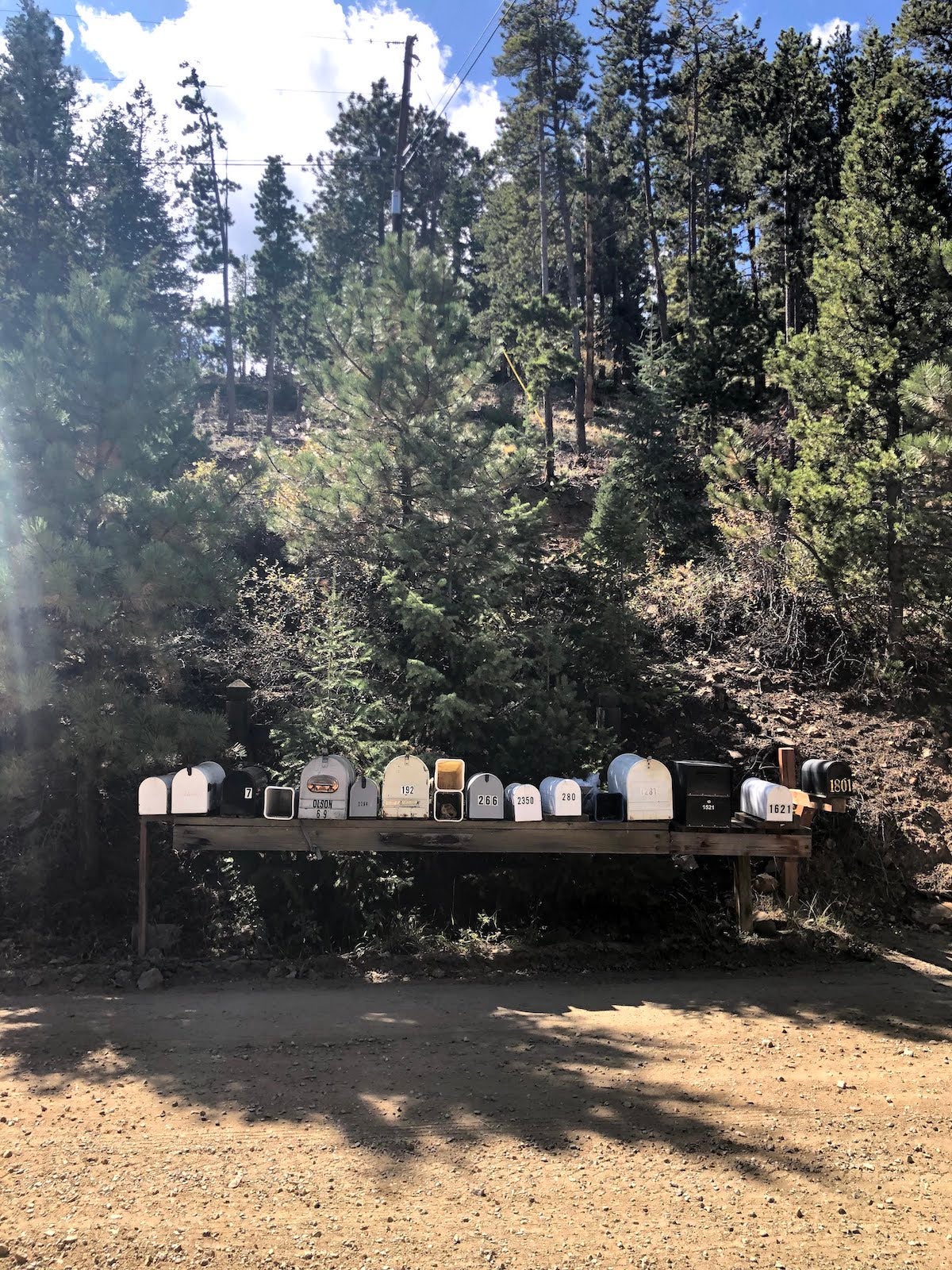 Several mailboxes aligned together on the side of a dirt road